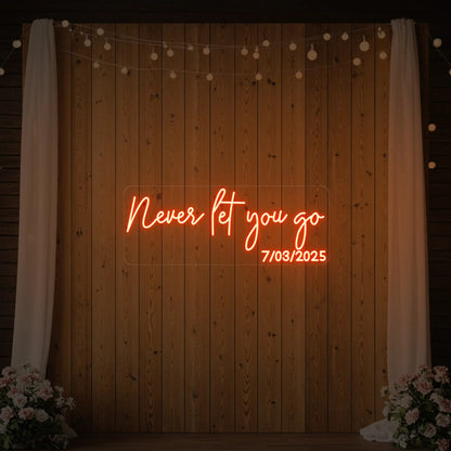  'Never Let You Go' neon sign glowing in golden yellow against a styled interior wall.