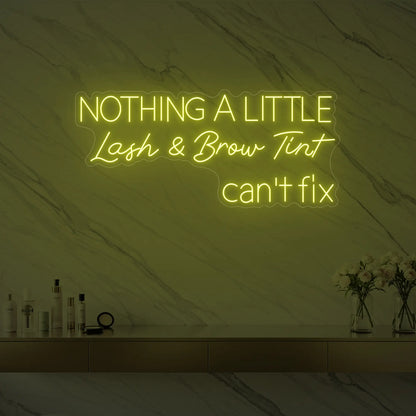 Photo of the 'Nothing a Little Lash & Brow Tint Can’t Fix' neon sign glowing in lemon yellow against a styled interior wall.