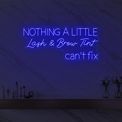 Photo of the 'Nothing a Little Lash & Brow Tint Can’t Fix' neon sign glowing in deep blue against a styled interior wall.