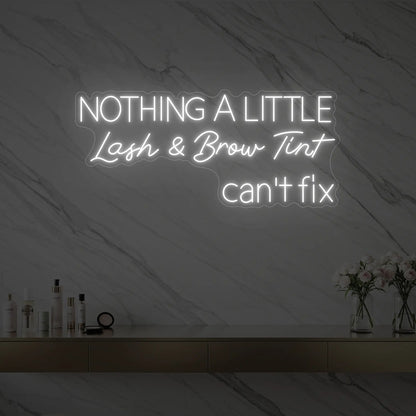 Photo of the 'Nothing a Little Lash & Brow Tint Can’t Fix' neon sign glowing in cool white against a styled interior wall.
