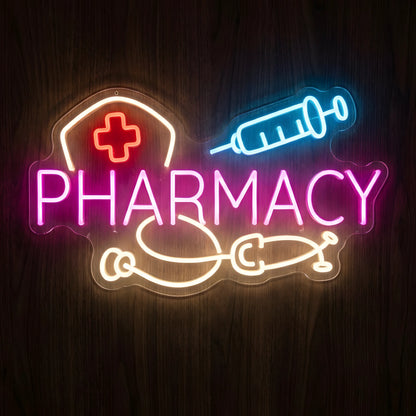 Pharmacy Nurse and Syringe LED Neon Sign featuring pink PHARMACY lettering, white nurse cap with red cross, blue syringe, and warm white stethoscope on a dark wooden wall.