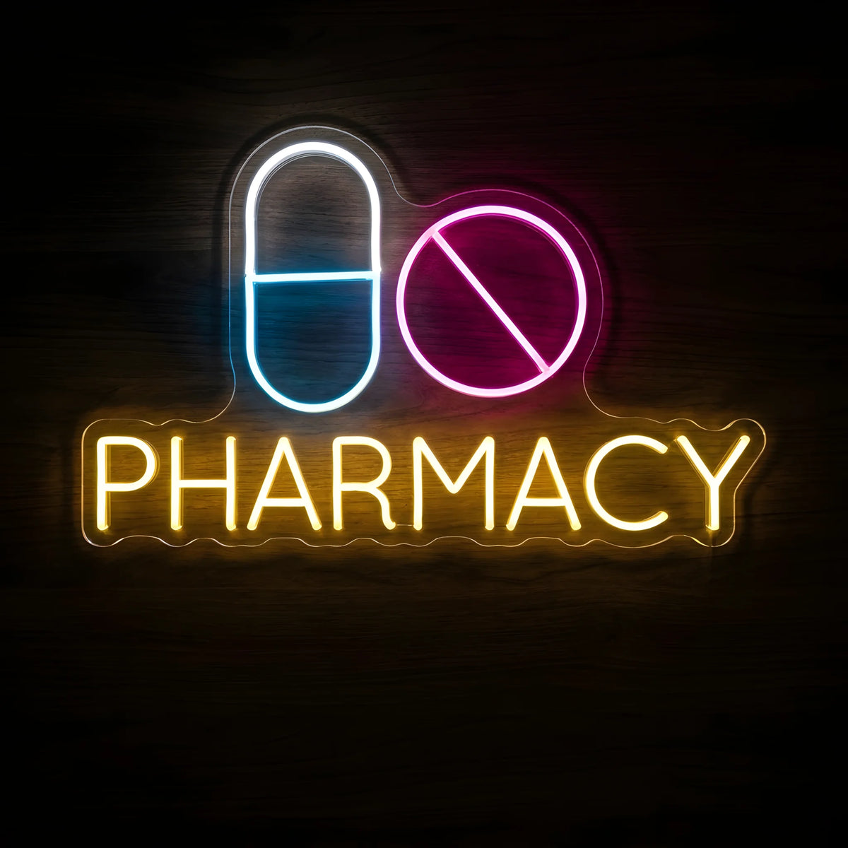 Pharmacy Pills LED Neon Sign featuring a blue and white capsule, pink round tablet, and yellow PHARMACY lettering on a dark wooden wall.