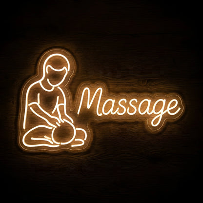 Professional Massage Therapist LED Neon Sign featuring a warm white illustration of a therapist massaging a client with elegant Massage script on clear cut-to-shape acrylic against a dark wooden wall.