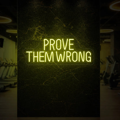  'PROVE THEM WRONG' neon sign glowing in lemon yellow against a styled interior wall.