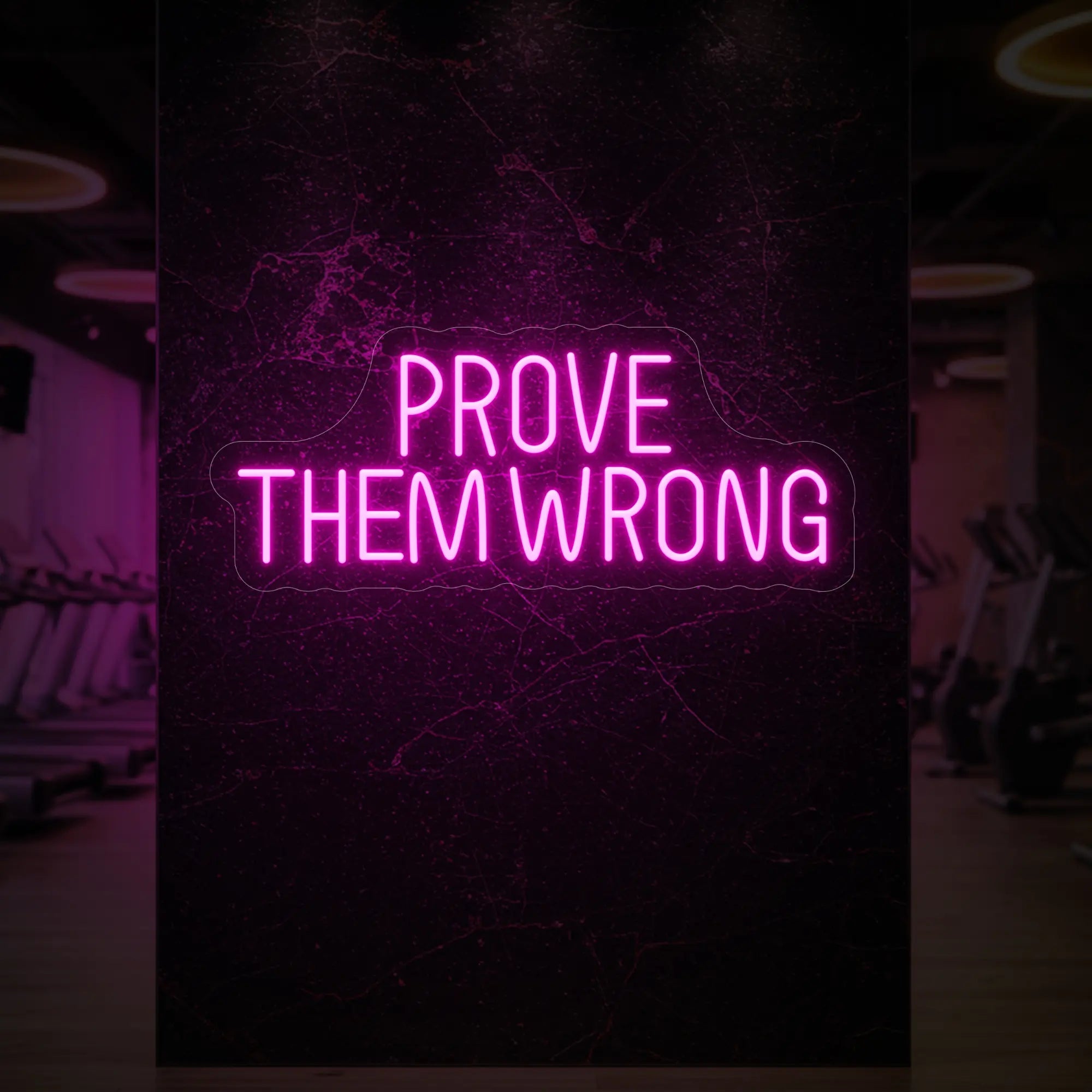  'PROVE THEM WRONG' neon sign glowing in light pink against a styled interior wall.