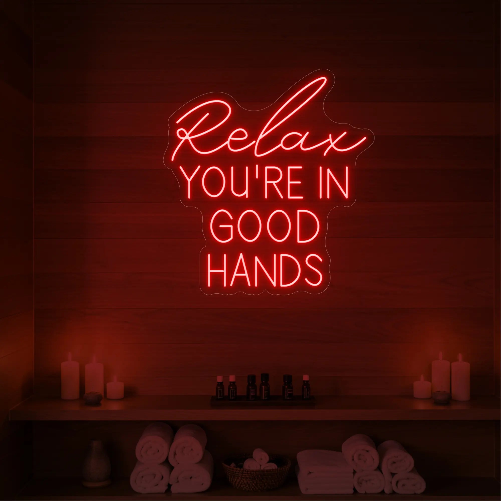 Photo of the 'Relax You're in Good Hands' neon sign glowing in red against a styled interior wall.