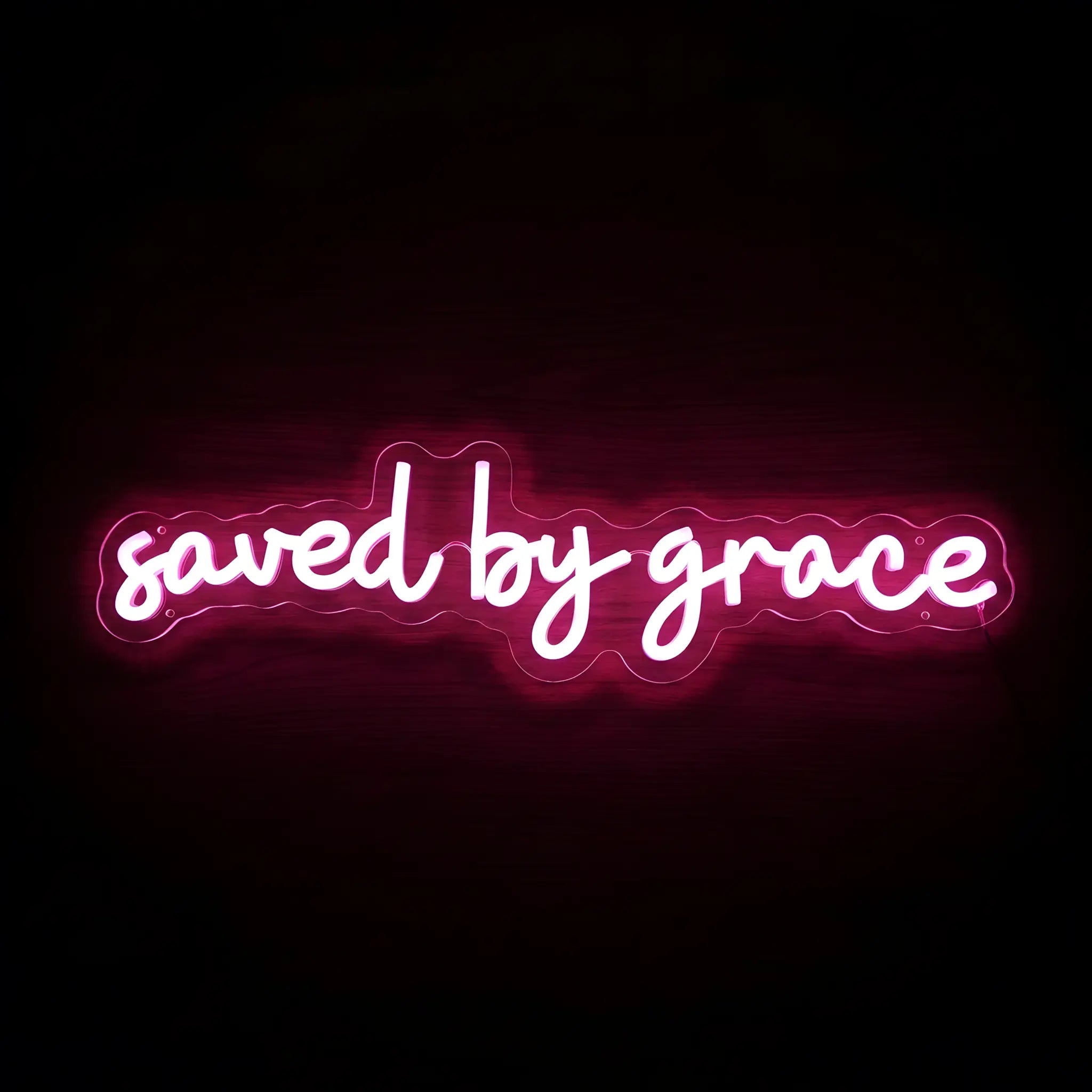 Saved by Grace LED neon sign with bright pink illumination on precision-cut acrylic backing, Christian wall decor featuring an inspirational faith message.