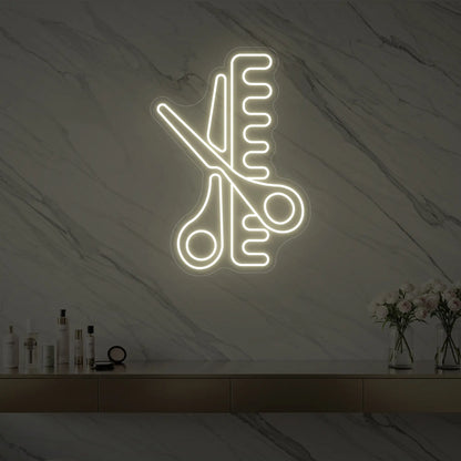 Photo of the 'Scissors and Comb' neon sign glowing in warm white against a styled interior wall.