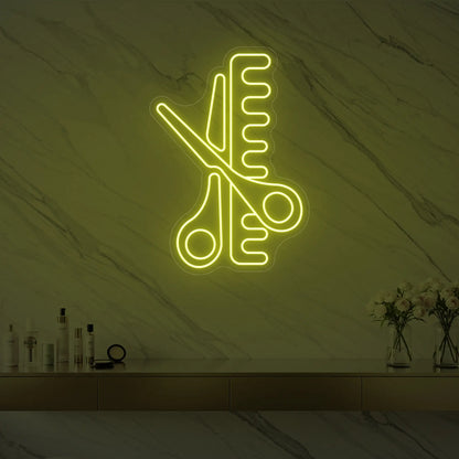 Photo of the 'Scissors and Comb' neon sign glowing in lemon yellow against a styled interior wall.