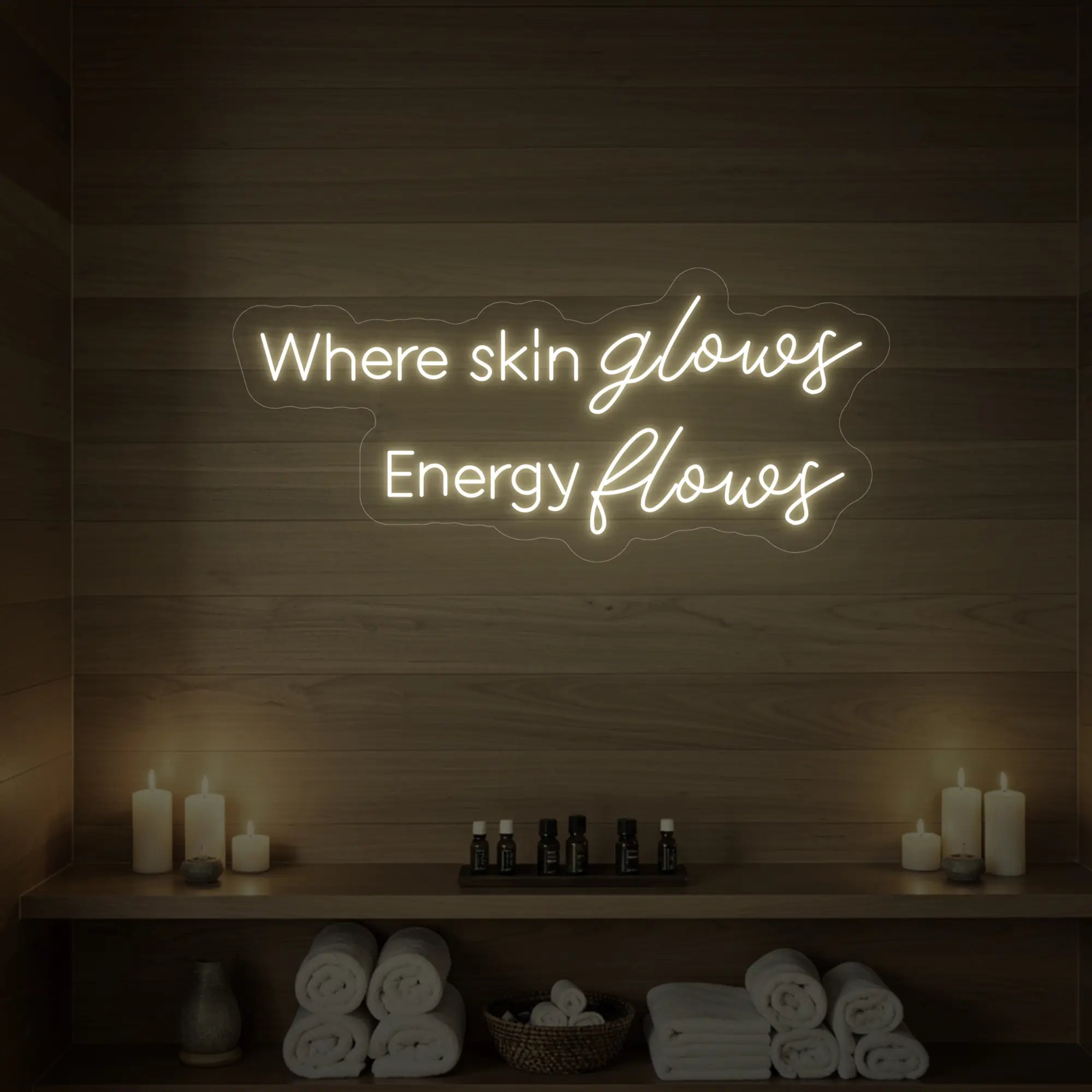 Photo of the 'Where Skin Glows, Energy Flows' neon sign glowing in warm white against a styled interior wall.
