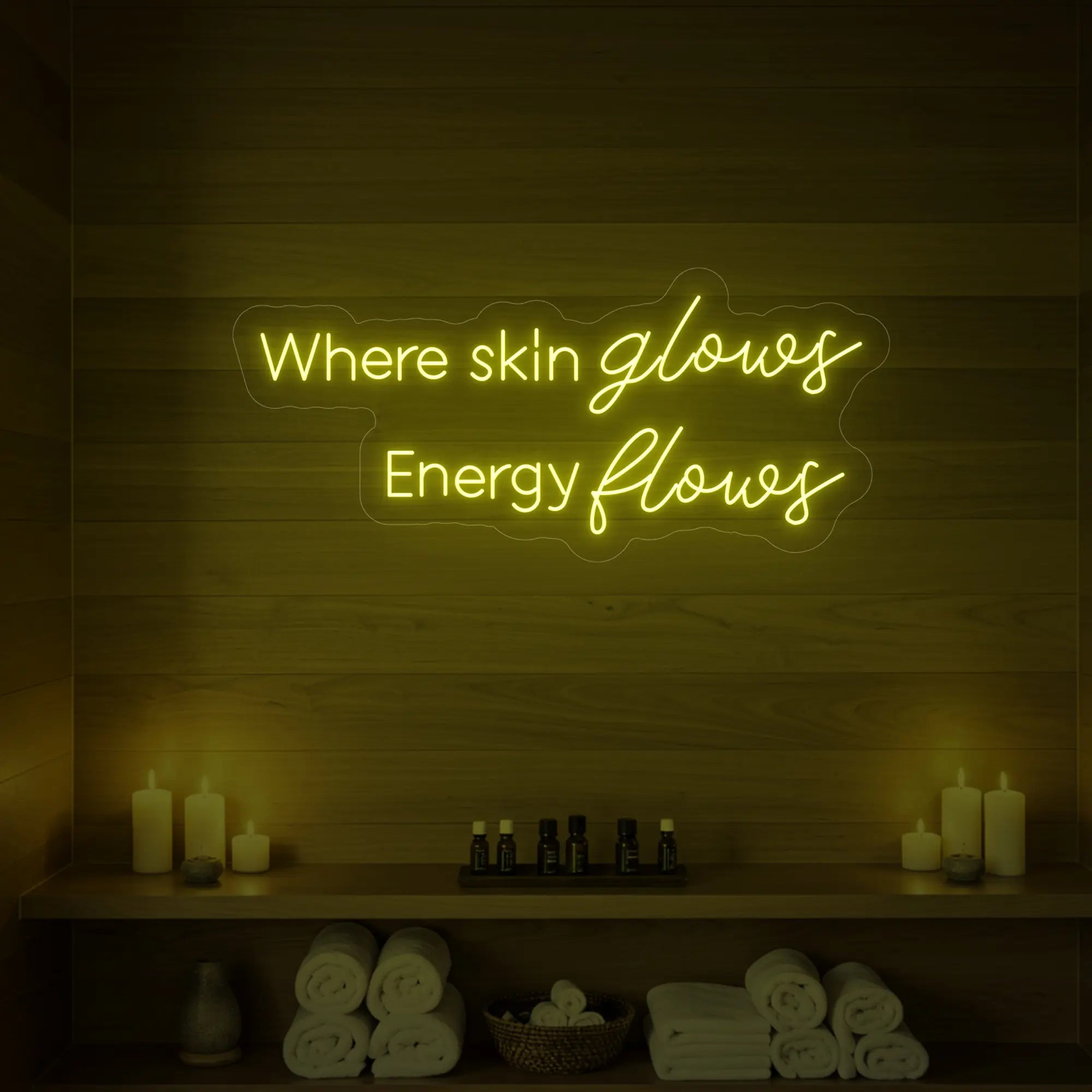 Photo of the 'Where Skin Glows, Energy Flows' neon sign glowing in lemon yellow against a styled interior wall.