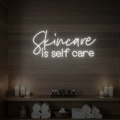 Photo of the 'Skincare is Self Care' neon sign glowing in cool white against a styled interior wall.