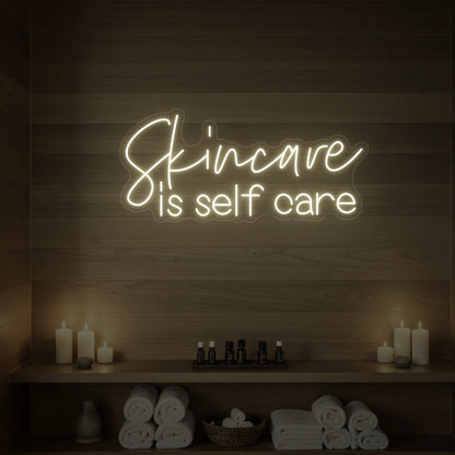 Photo of the 'Skincare is Self Care' neon sign glowing in warm white against a styled interior wall.