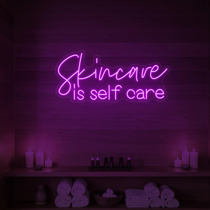 Photo of the 'Skincare is Self Care' neon sign glowing in deep pink against a styled interior wall.