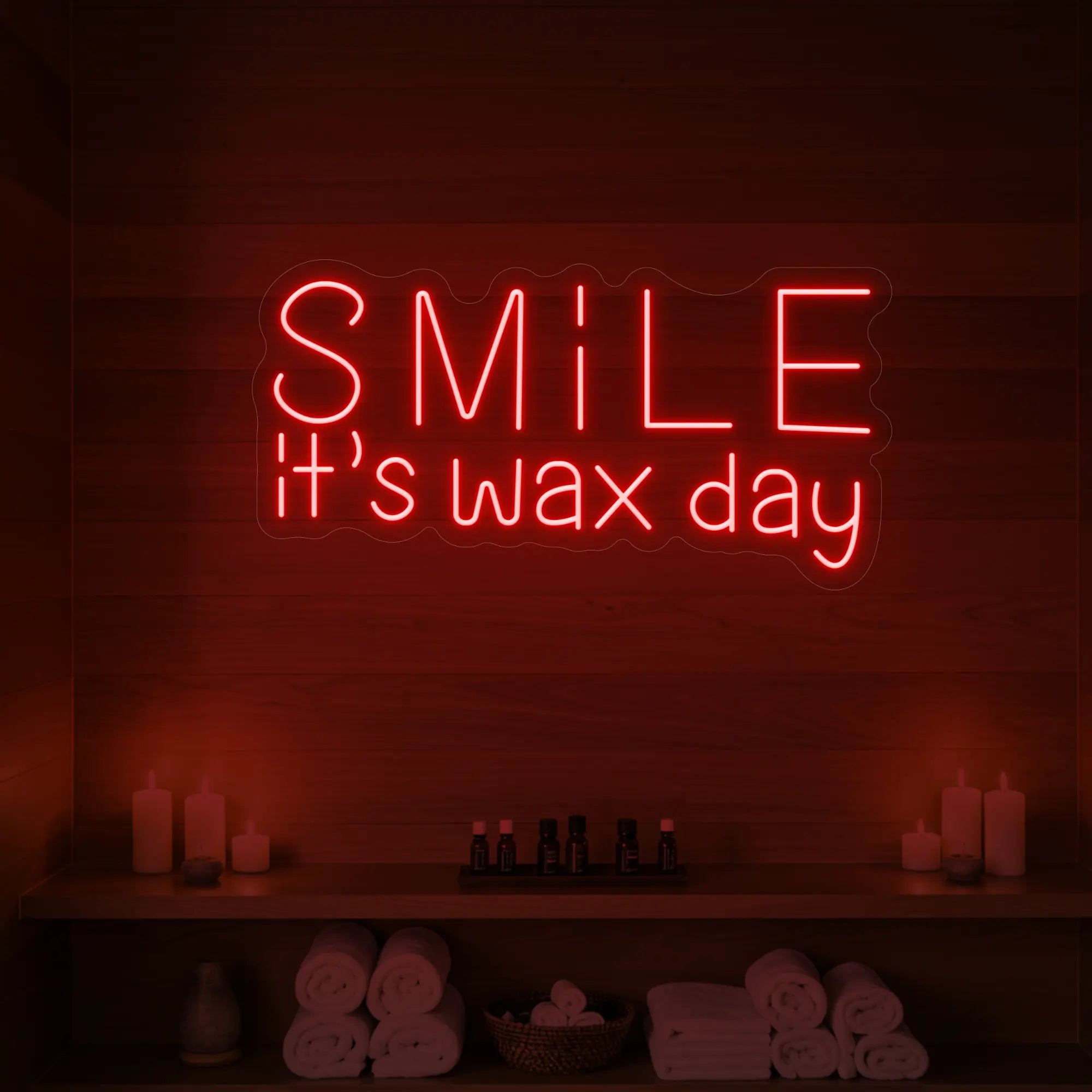 Photo of the 'Smile It’s Wax Day' neon sign glowing in red against a styled interior wall.