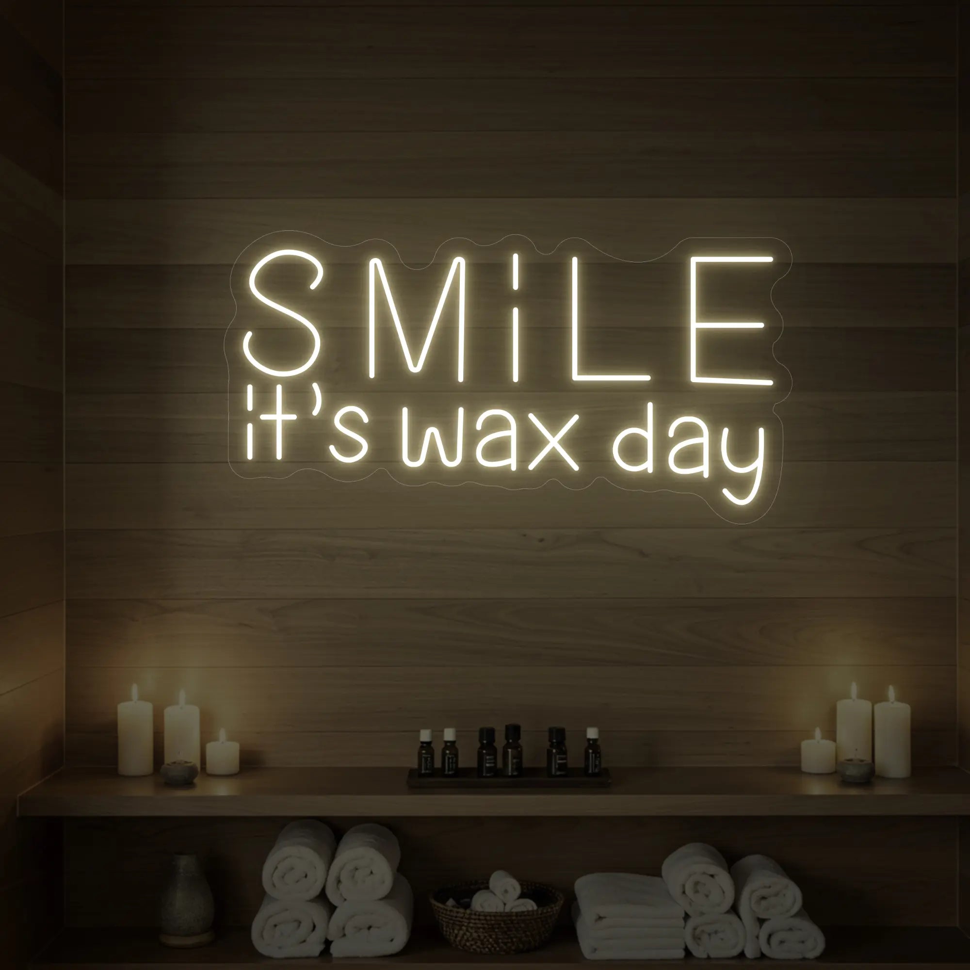 Photo of the 'Smile It’s Wax Day' neon sign glowing in warm white against a styled interior wall.