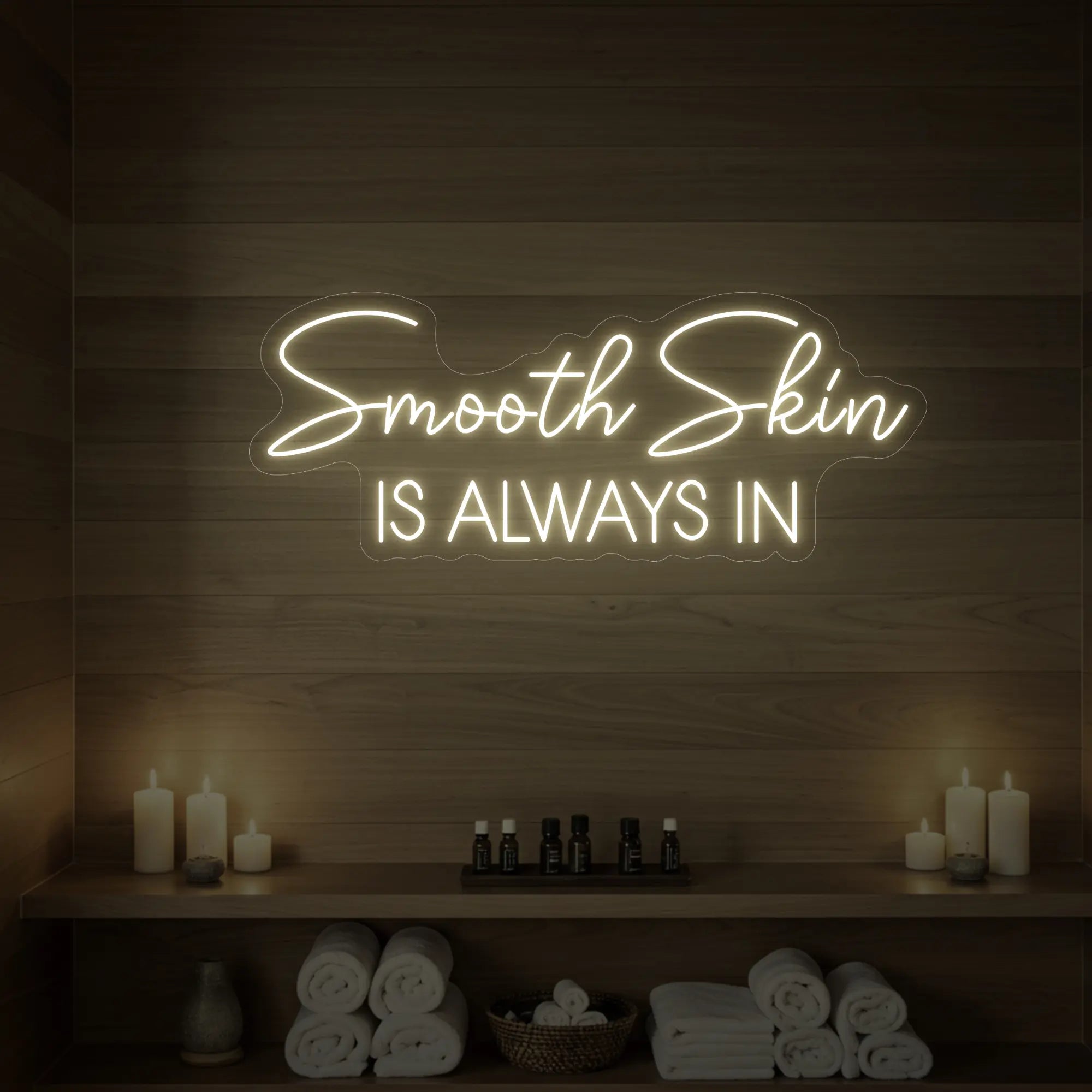 Photo of the 'Smooth Skin Is Always In' neon sign glowing in warm white against a styled interior wall.