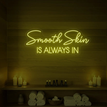 Photo of the 'Smooth Skin Is Always In' neon sign glowing in lemon yellow against a styled interior wall.