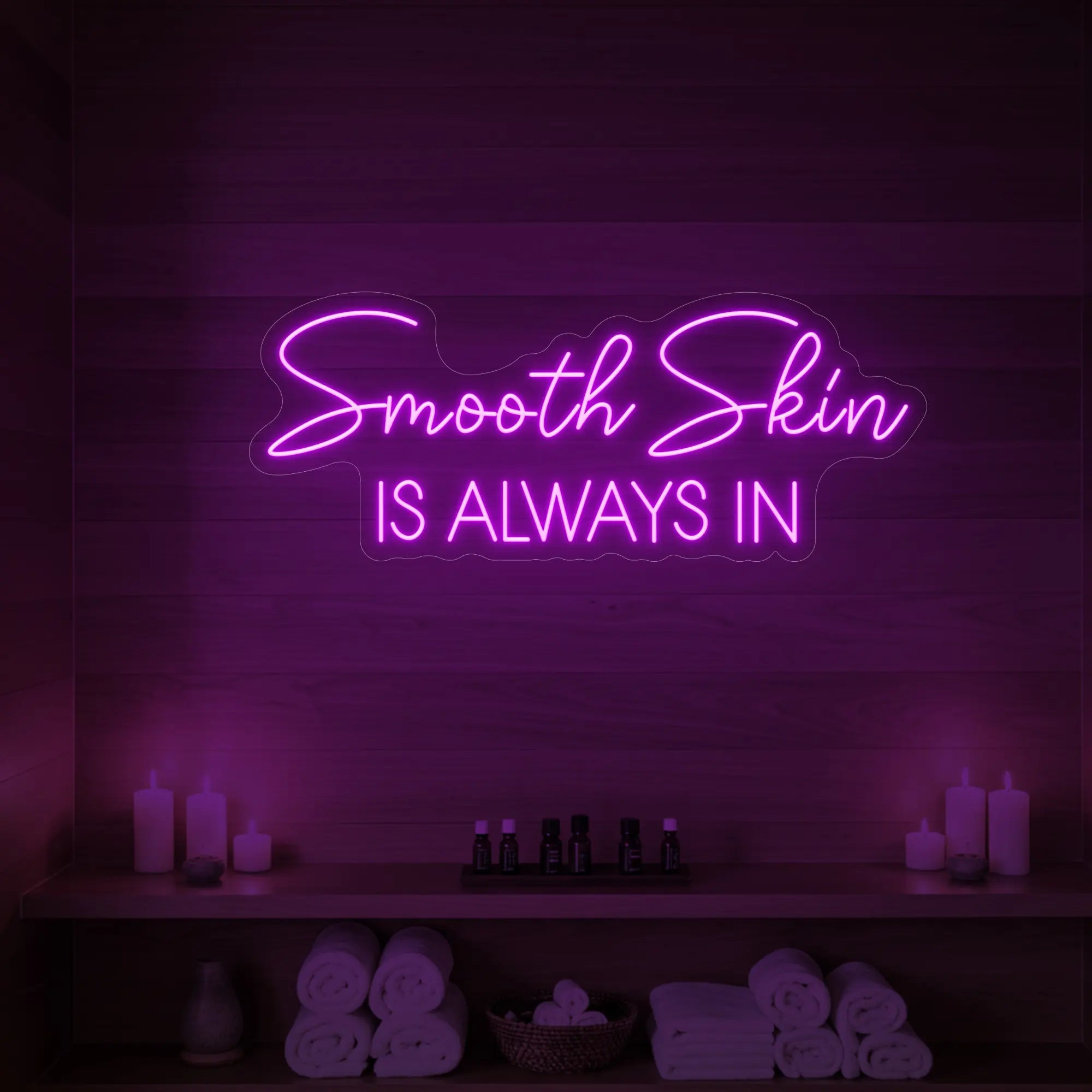 Photo of the 'Smooth Skin Is Always In' neon sign glowing in deep pink against a styled interior wall.
