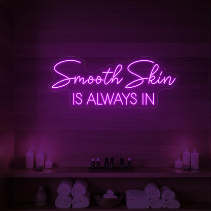 Photo of the 'Smooth Skin Is Always In' neon sign glowing in deep pink against a styled interior wall.