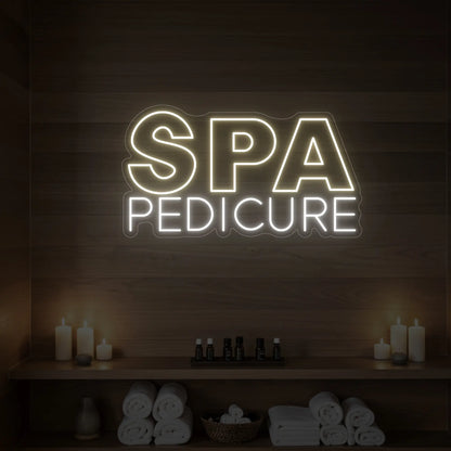 Photo of the 'Spa Pedicure' neon sign glowing in warm white against a styled interior wall.

