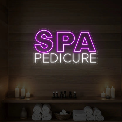 Photo of the 'Spa Pedicure' neon sign glowing in deep pink against a styled interior wall.