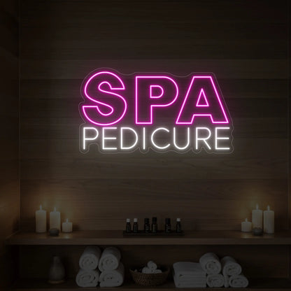 Photo of the 'Spa Pedicure' neon sign glowing in light pink against a styled interior wall.