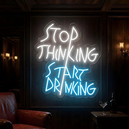 Photo of the 'Stop Thinking Start Drinking Version 2' neon sign glowing in multi-color against a modern bar-inspired wall.