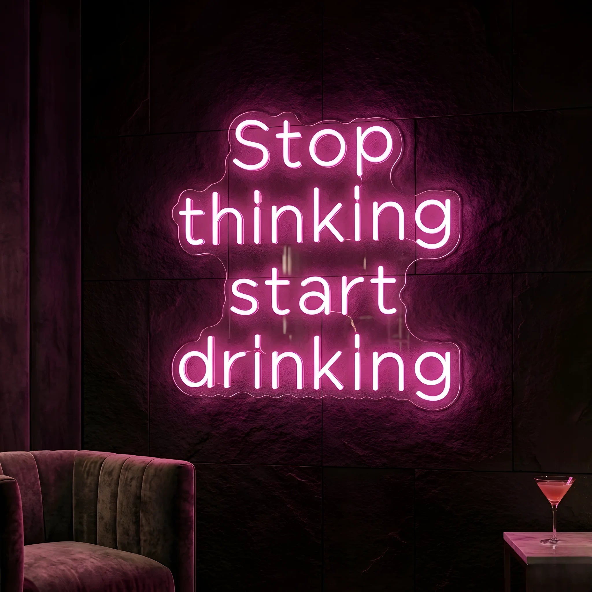 Photo of the 'Stop Thinking Start Drinking Version 1' neon sign glowing in pink against a nightlife-inspired wall.