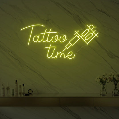 Photo of the 'Tattoo Time' neon sign glowing in lemon yellow against a styled interior wall.
