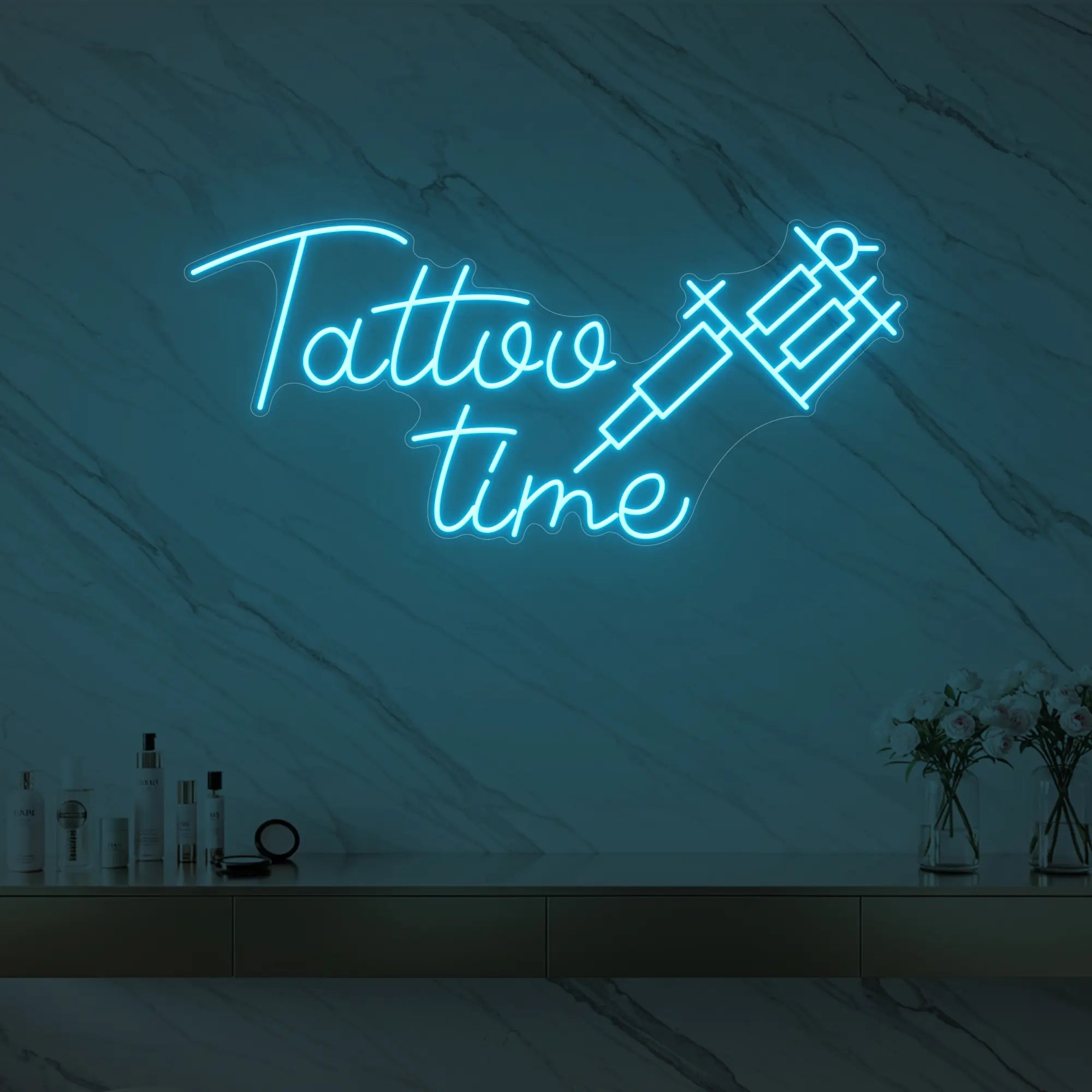 Photo of the 'Tattoo Time' neon sign glowing in ice blue against a styled interior wall.