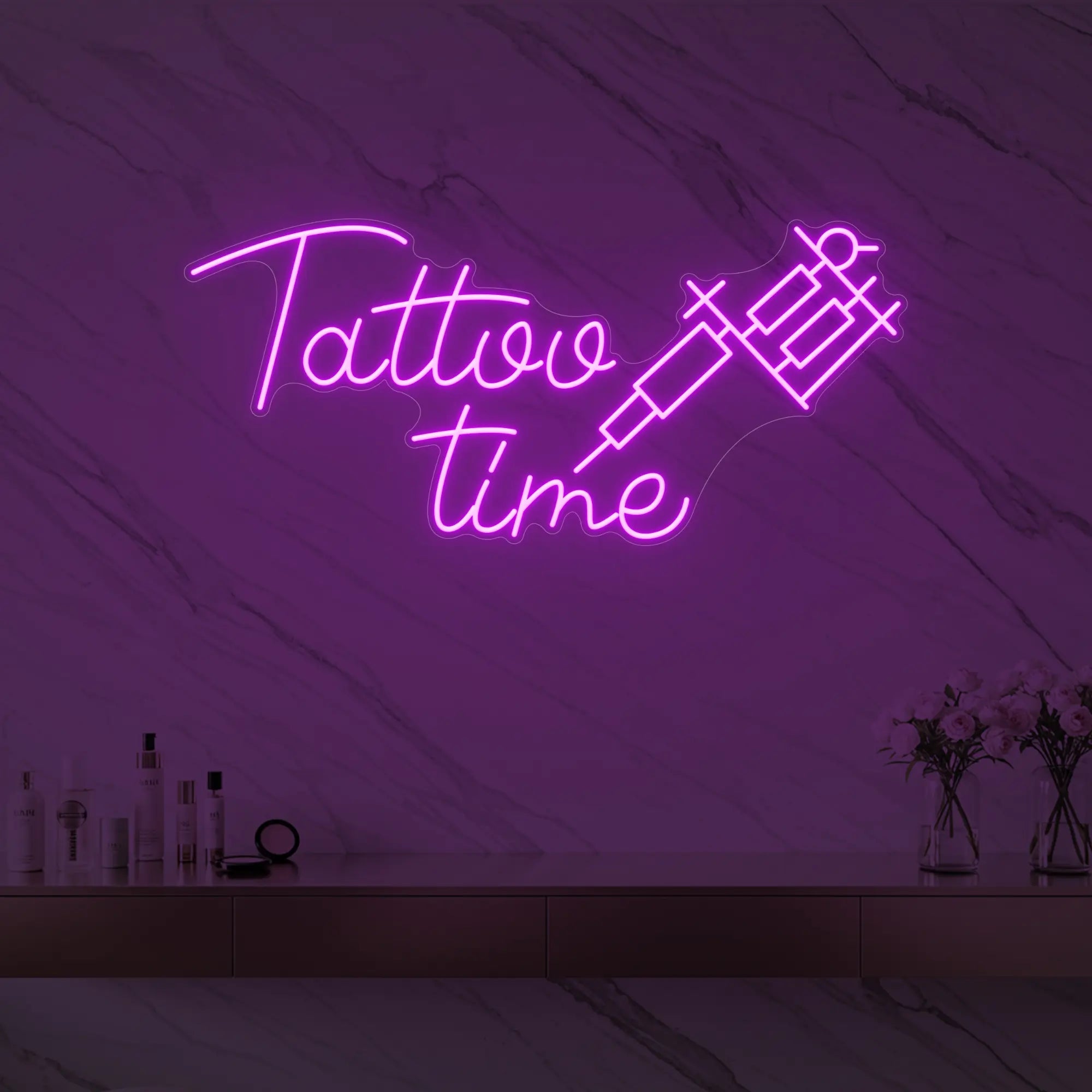 Photo of the 'Tattoo Time' neon sign glowing in deep pink against a styled interior wall.