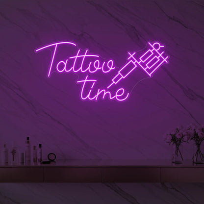 Photo of the 'Tattoo Time' neon sign glowing in deep pink against a styled interior wall.