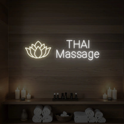 Photo of the 'Thai Massage' neon sign glowing in warm white against a styled interior wall.
