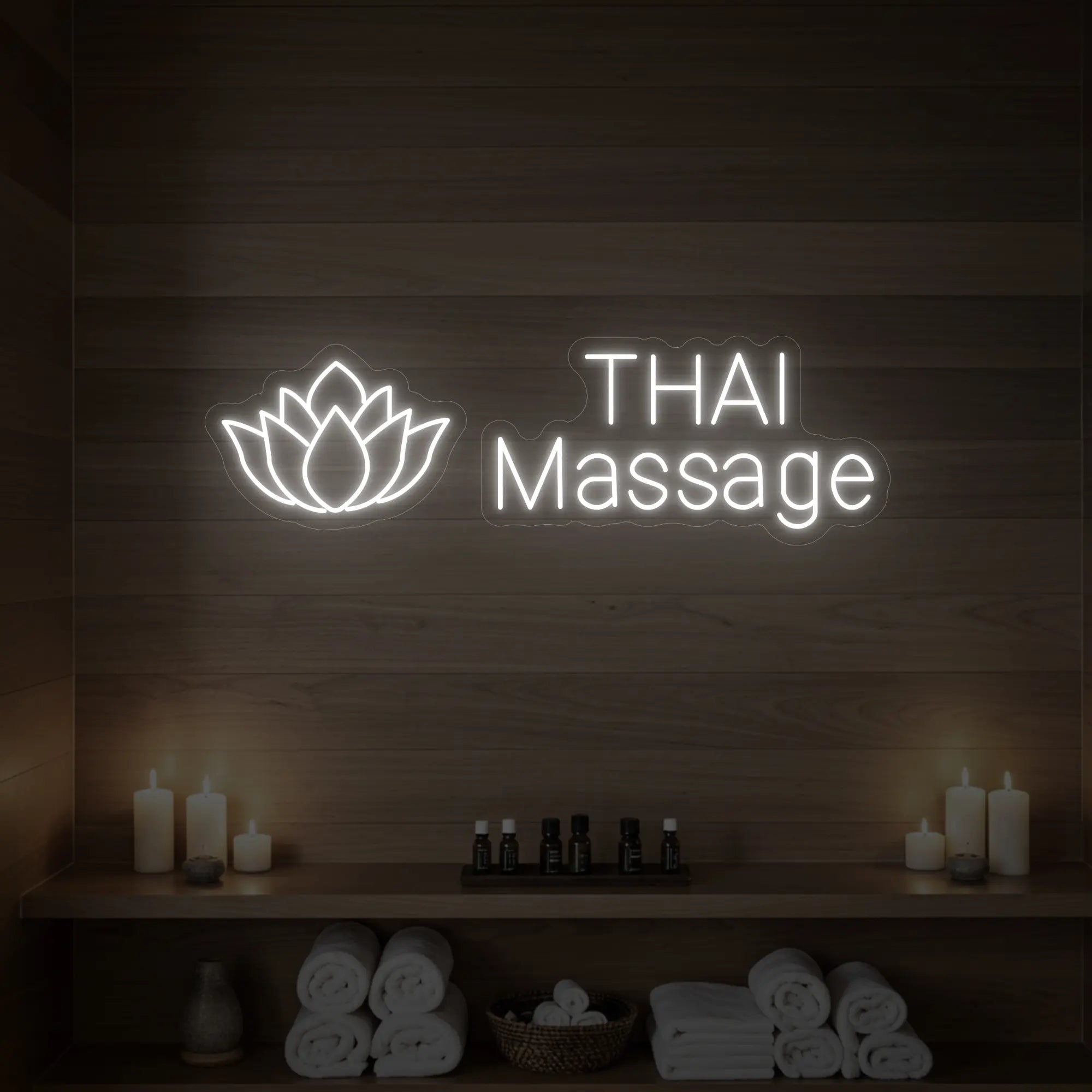Photo of the 'Thai Massage' neon sign glowing in cool white against a styled interior wall.