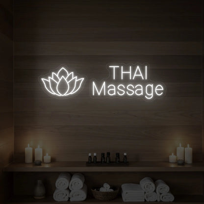 Photo of the 'Thai Massage' neon sign glowing in cool white against a styled interior wall.