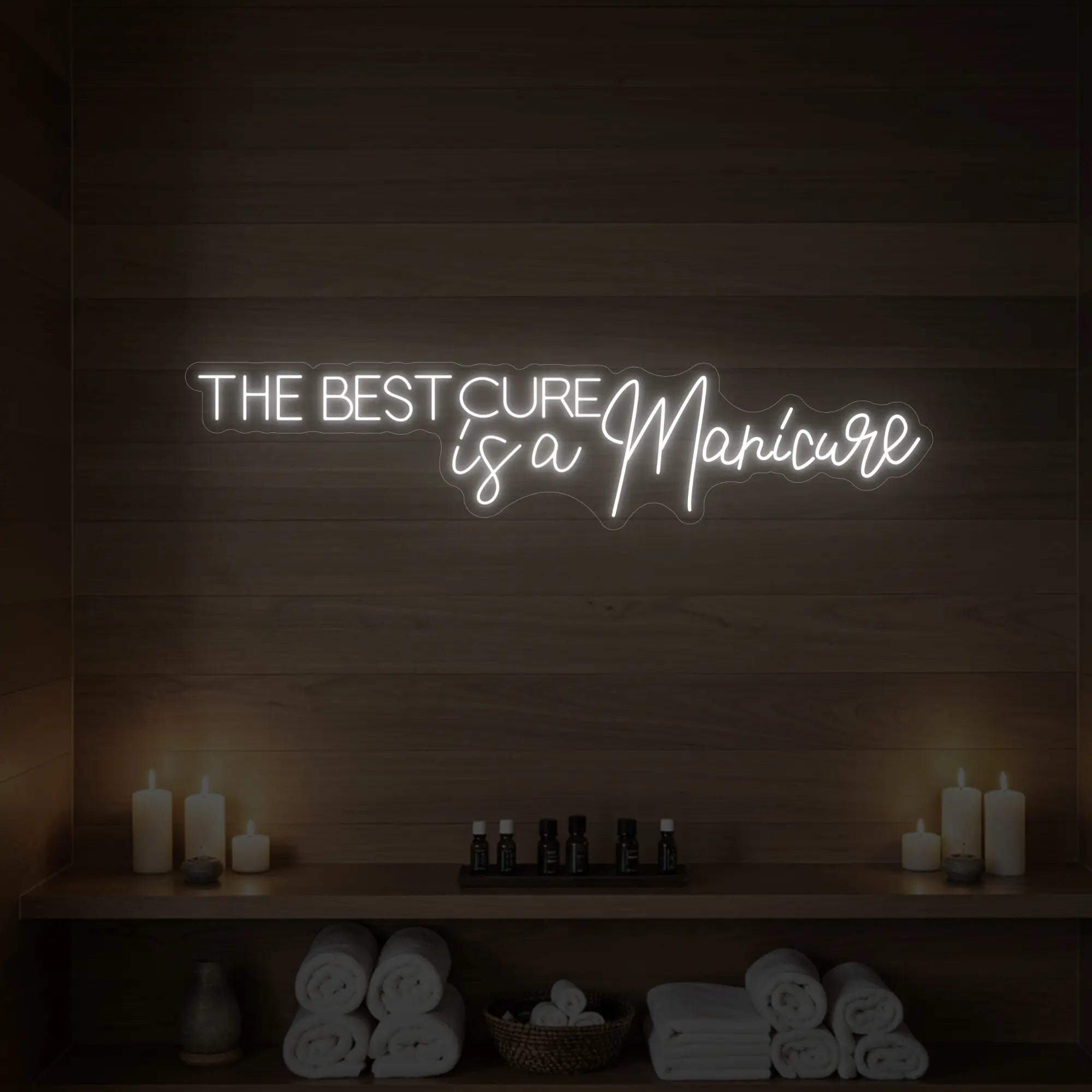 Photo of the 'The Best Cure is a Manicure' neon sign glowing in cool white against a styled interior wall.