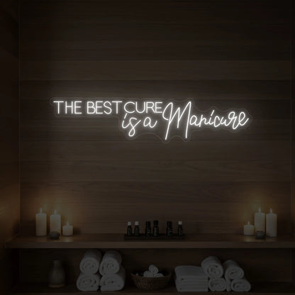 Photo of the 'The Best Cure is a Manicure' neon sign glowing in cool white against a styled interior wall.