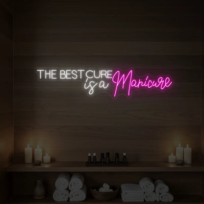 Photo of the 'The Best Cure is a Manicure' neon sign glowing in light pink against a styled interior wall.