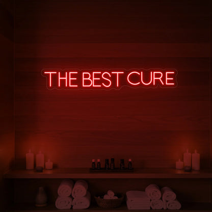 Photo of the 'The Best Cure' neon sign glowing in red against a styled interior wall.