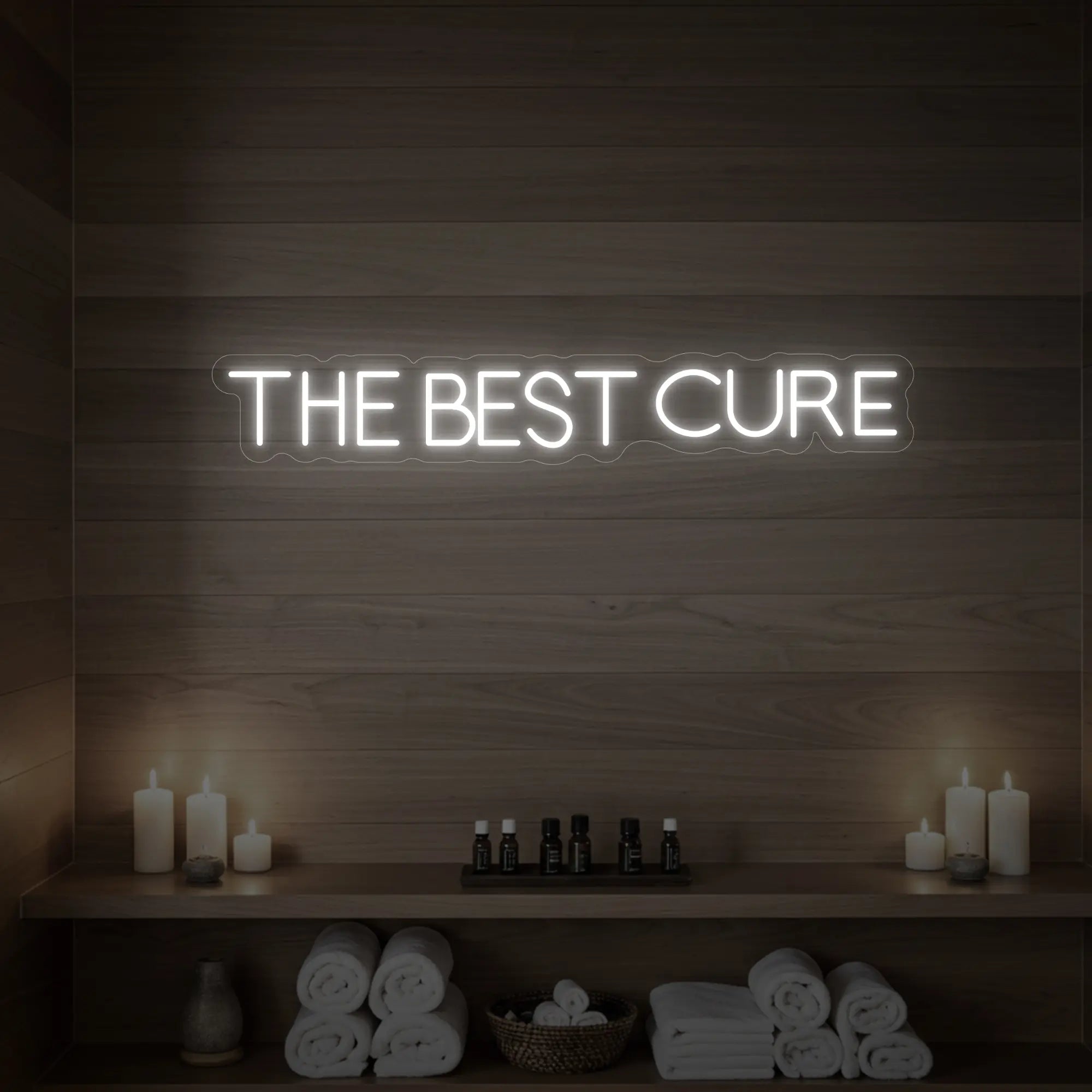 Photo of the 'The Best Cure' neon sign glowing in cool white against a styled interior wall.