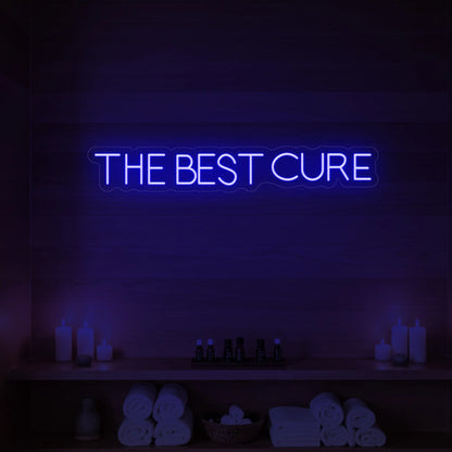 Photo of the 'The Best Cure' neon sign glowing in deep blue against a styled interior wall.