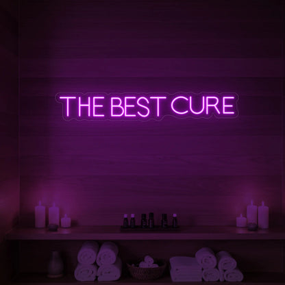 Photo of the 'The Best Cure' neon sign glowing in deep pink against a styled interior wall.