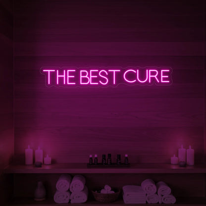 Photo of the 'The Best Cure' neon sign glowing in light pink against a styled interior wall.