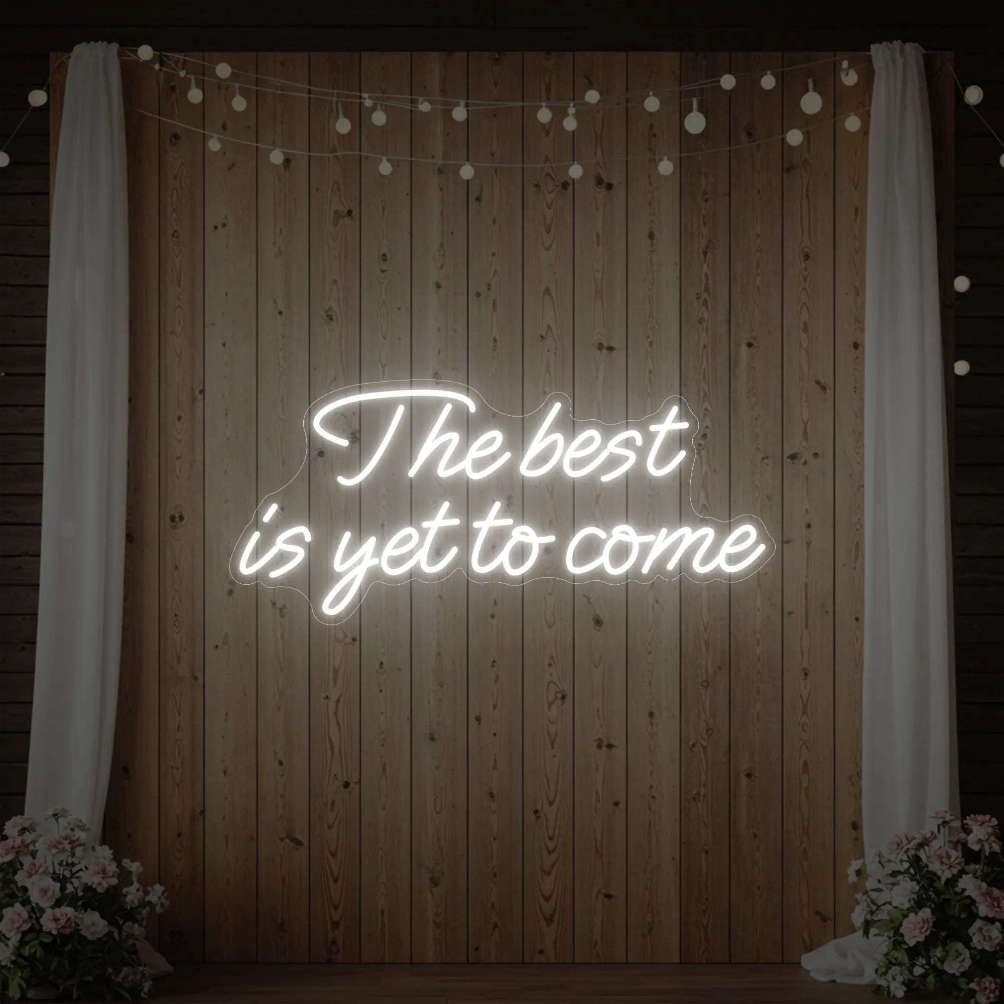 'The Best Is Yet To Come' neon sign glowing in cool white against a styled interior wall.