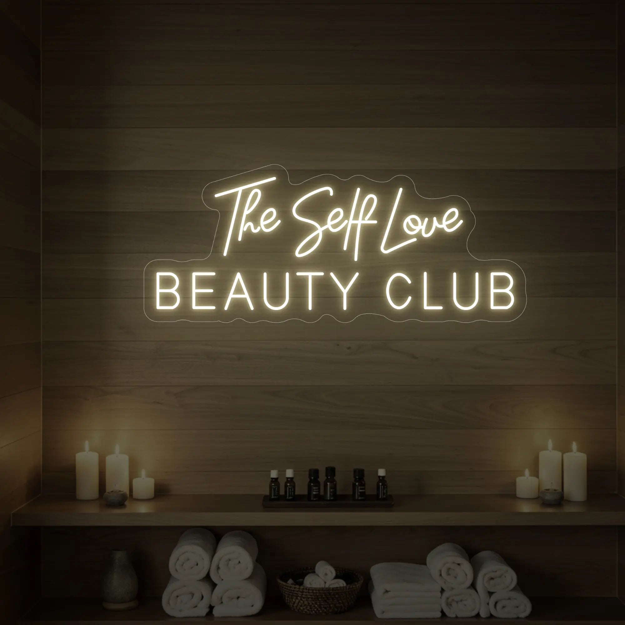 Photo of the 'The Self Love Beauty Club' neon sign glowing in warm white against a styled interior wall.