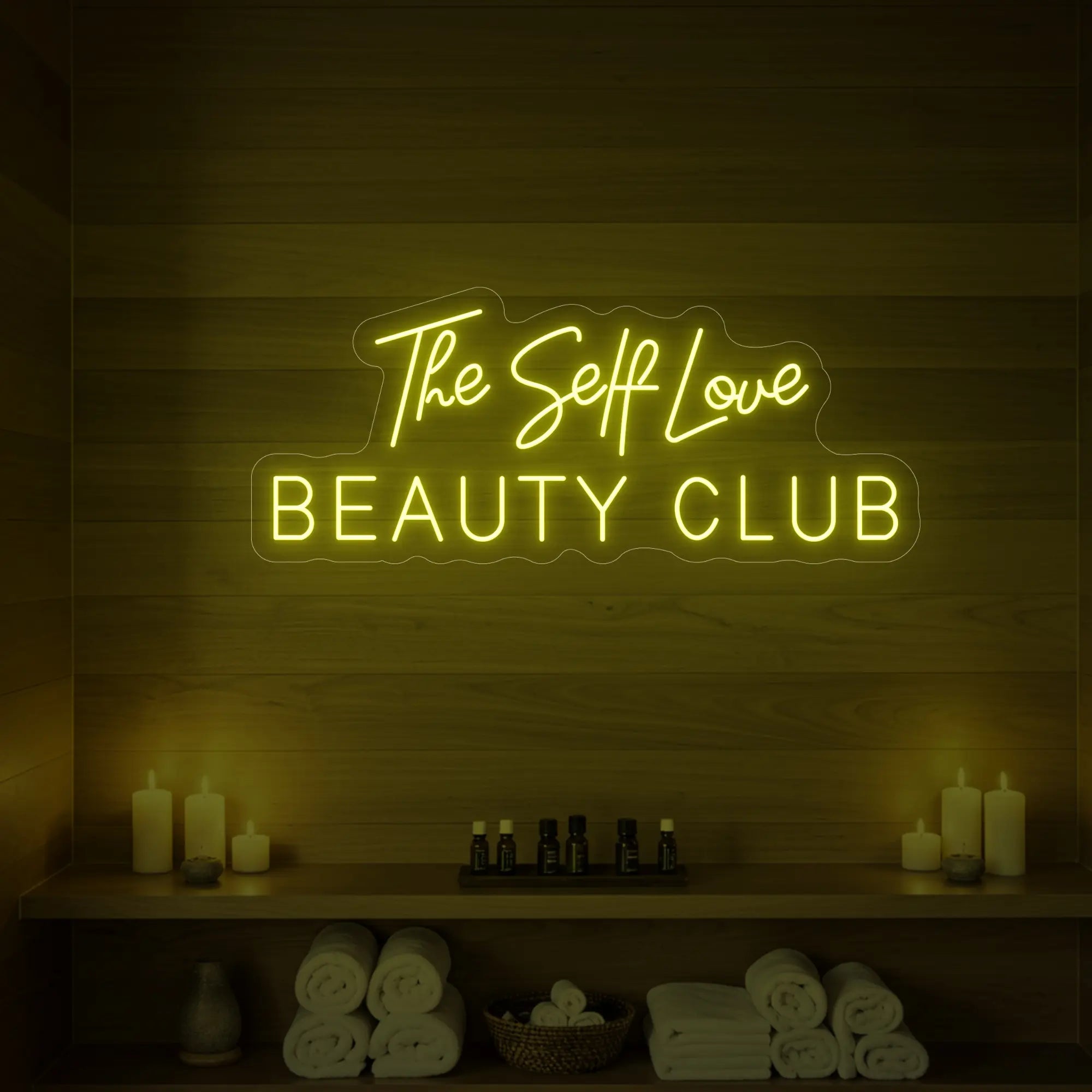 Photo of the 'The Self Love Beauty Club' neon sign glowing in lemon yellow against a styled interior wall.