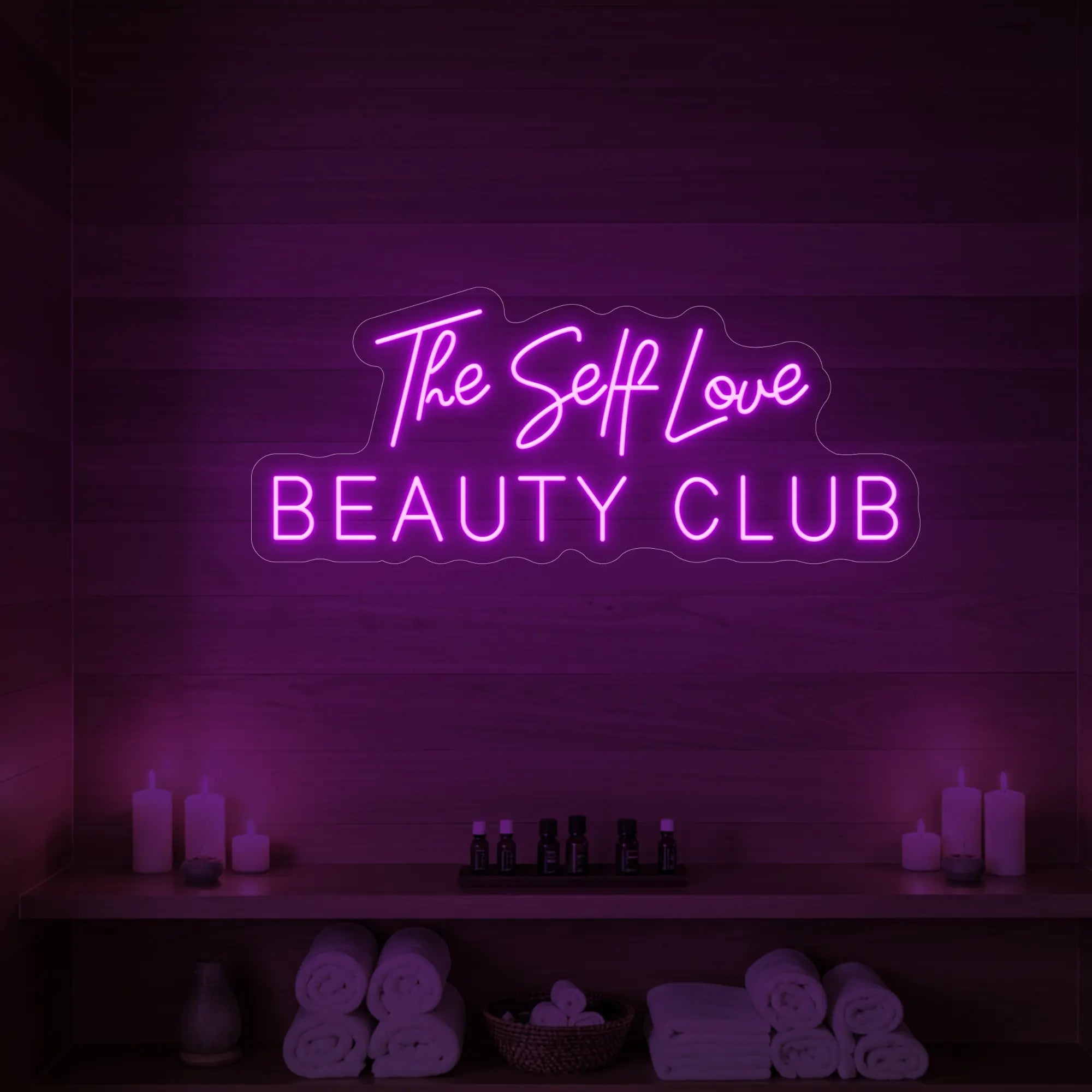 Photo of the 'The Self Love Beauty Club' neon sign glowing in deep pink against a styled interior wall.