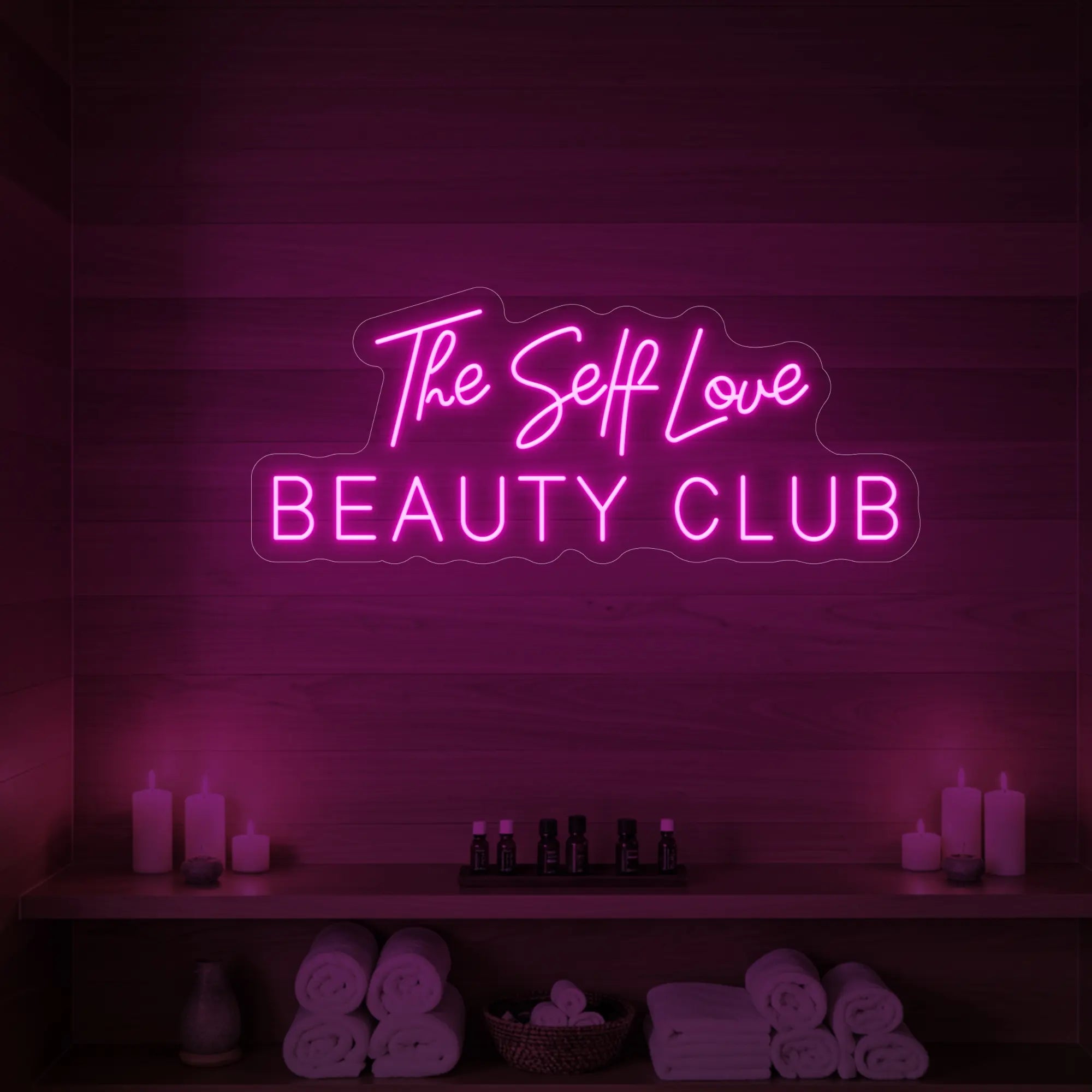 Photo of the 'The Self Love Beauty Club' neon sign glowing in light pink against a styled interior wall.