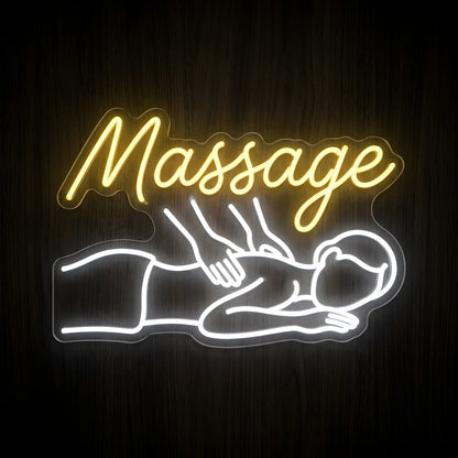 Therapeutic Body Massage LED Neon Sign featuring warm yellow cursive Massage lettering and a glowing white outline of a person receiving a back massage on clear cut-to-shape acrylic against a dark wooden wall.